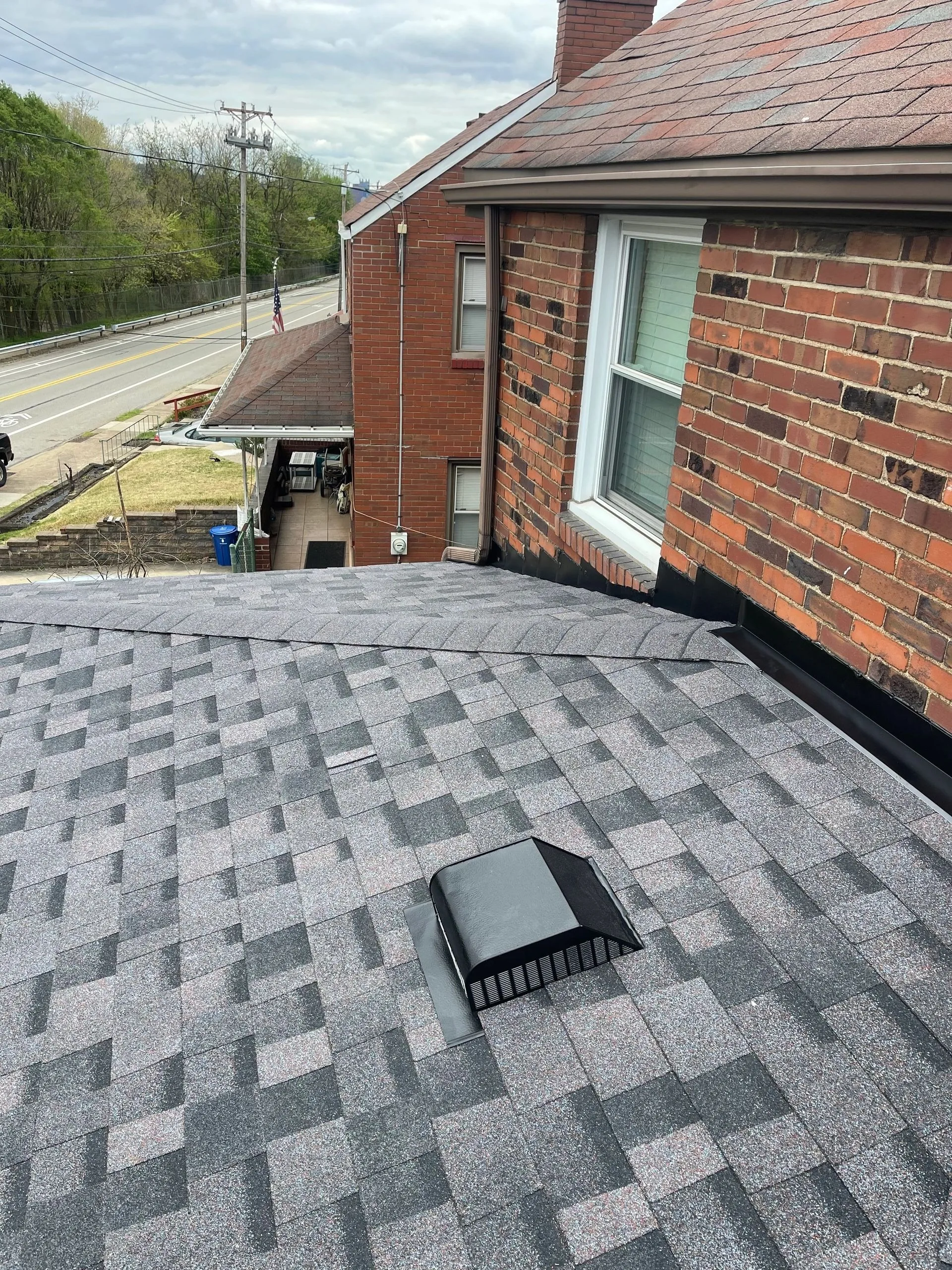 New grey architectural shingles and a properly seated roof vent on a brick home