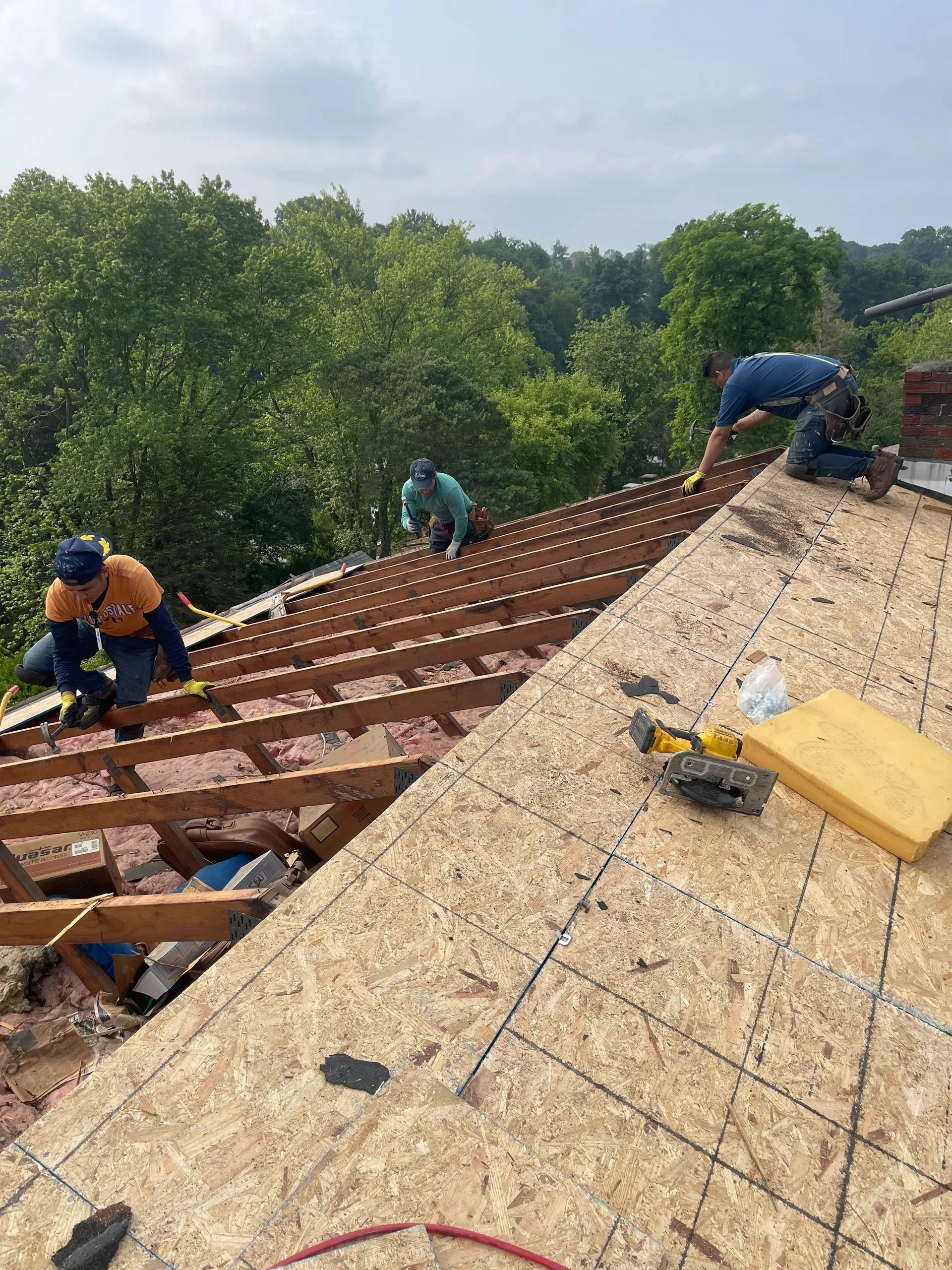 Crew mid tear-off with new plywood decking exposed across the roof